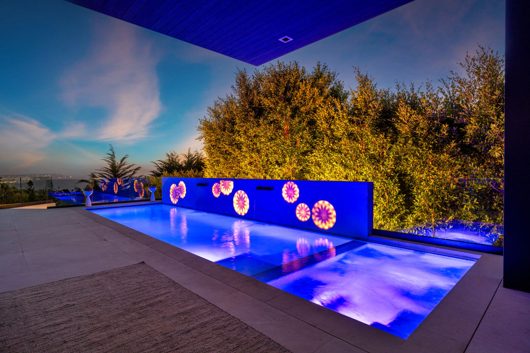Luxury pool and spa with illuminated feature wall at night