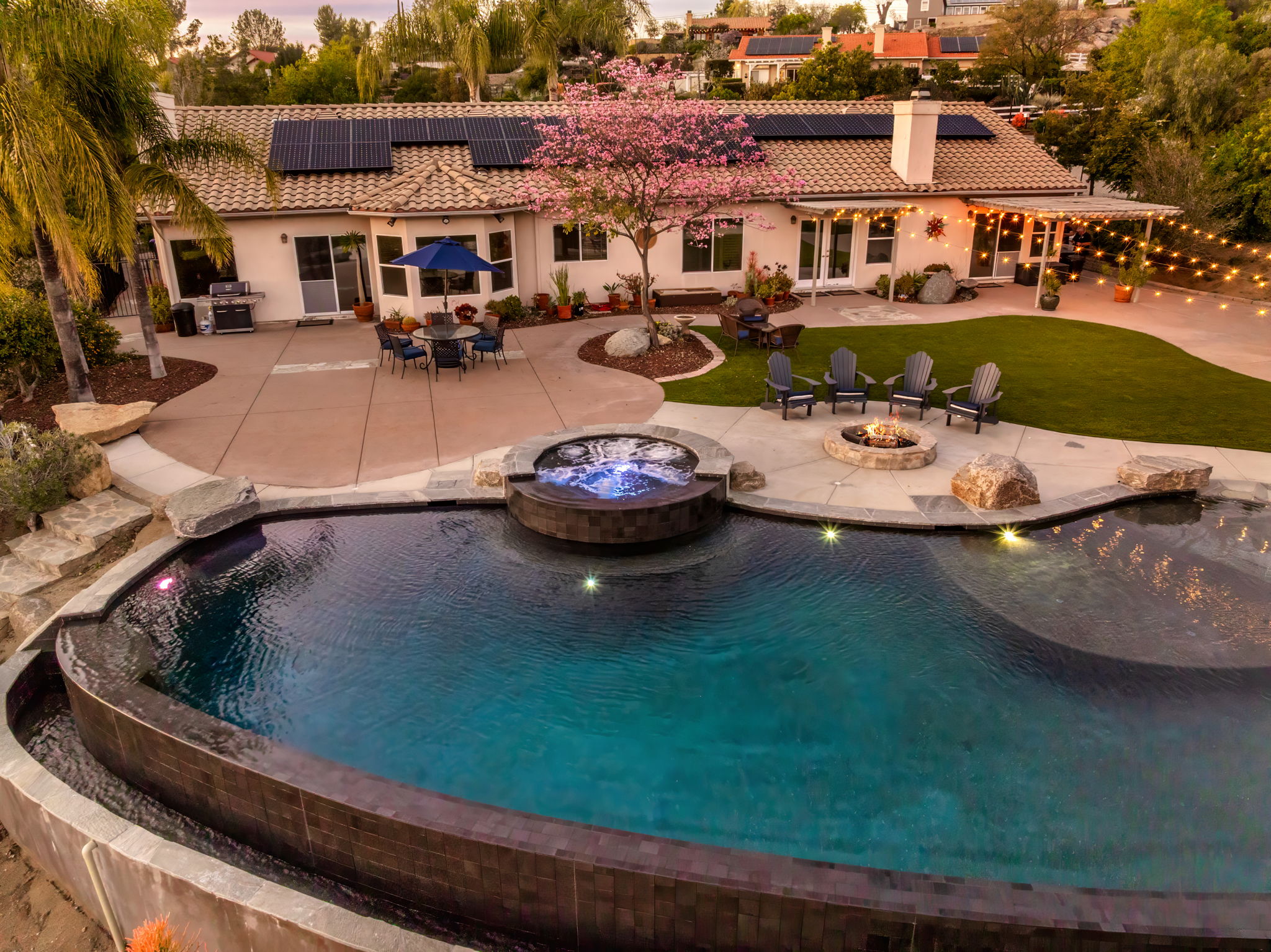 Freeform pool with raised spa, fire pit, and patio seating