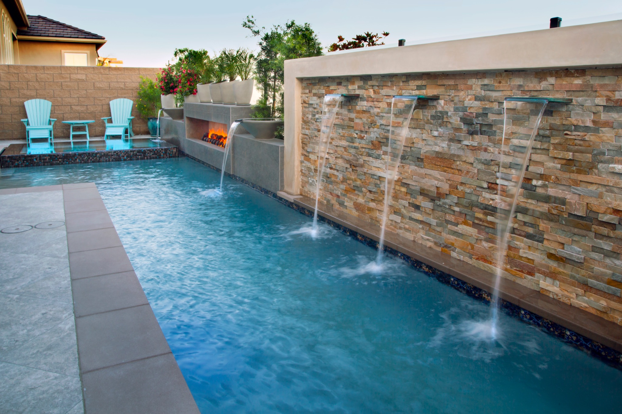 Modern pool with stacked stone water wall and fire feature