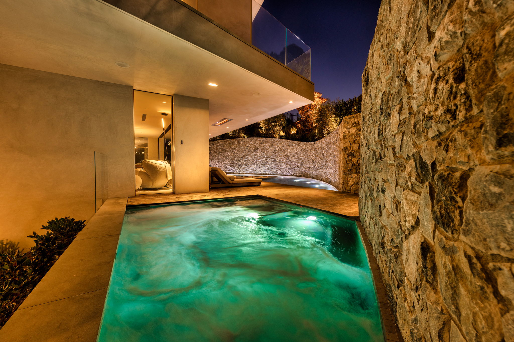 Modern plunge pool with natural stone wall and underwater lighting