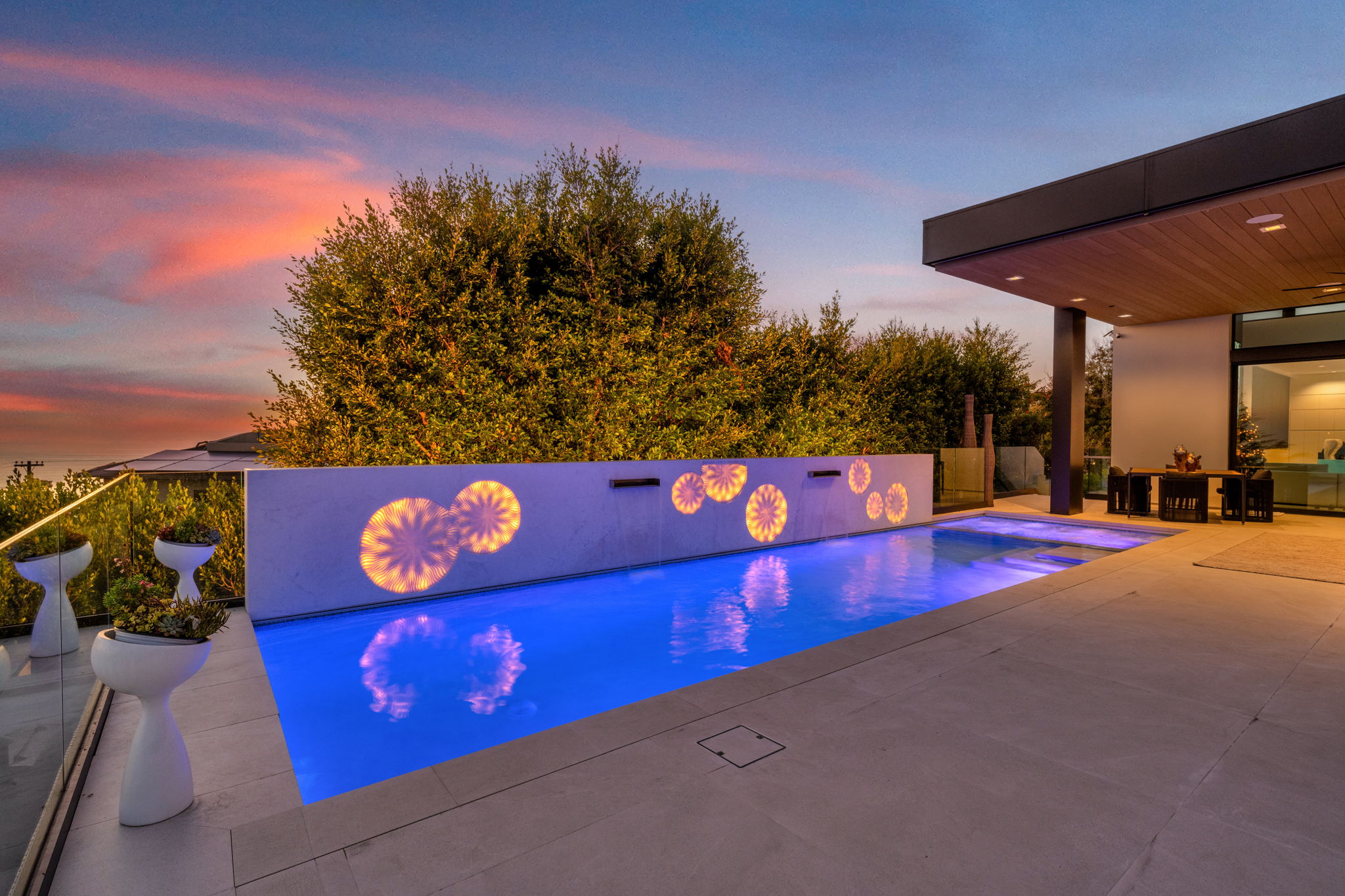 Modern lap pool with decorative wall lighting at sunset