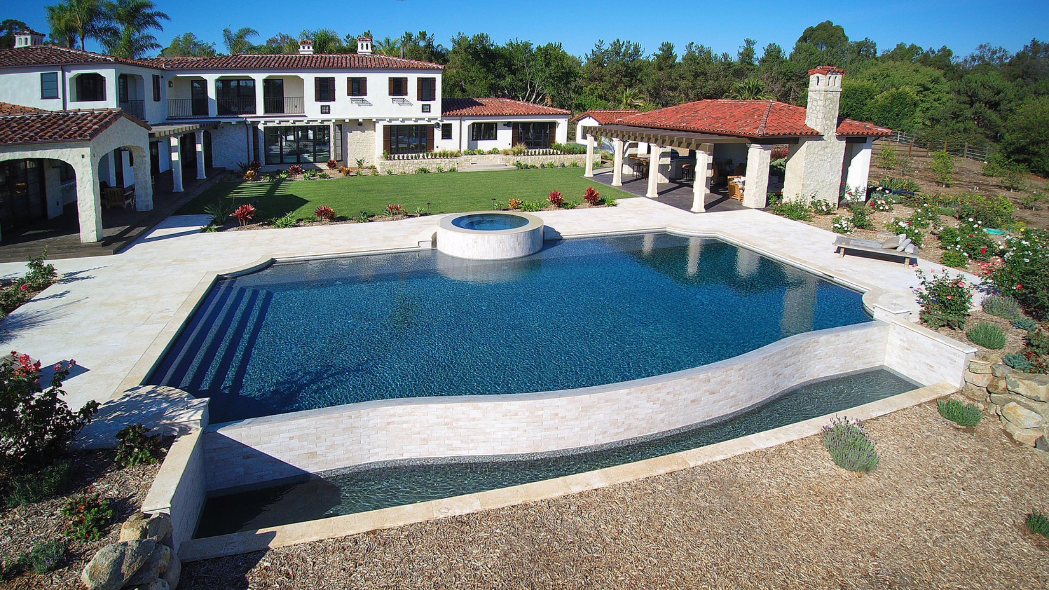 Large estate pool with raised spa and travertine deck