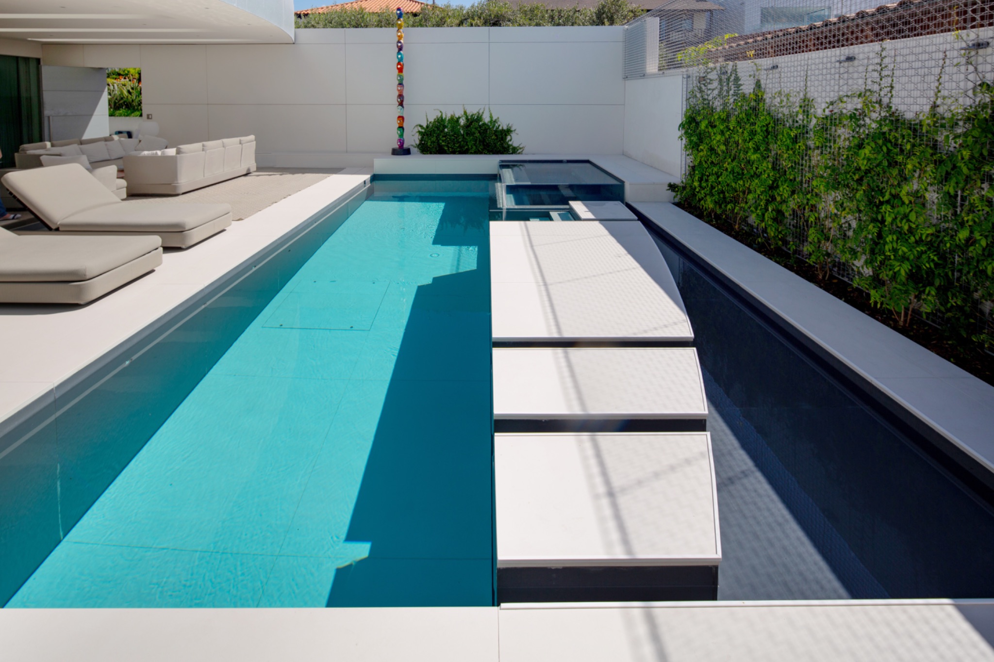Modern lap pool with stepping pads and courtyard lounge area