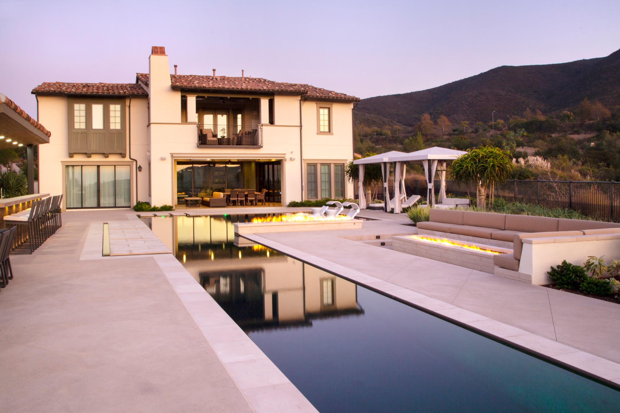 Geometric pool with fire features and sunken lounge at dusk