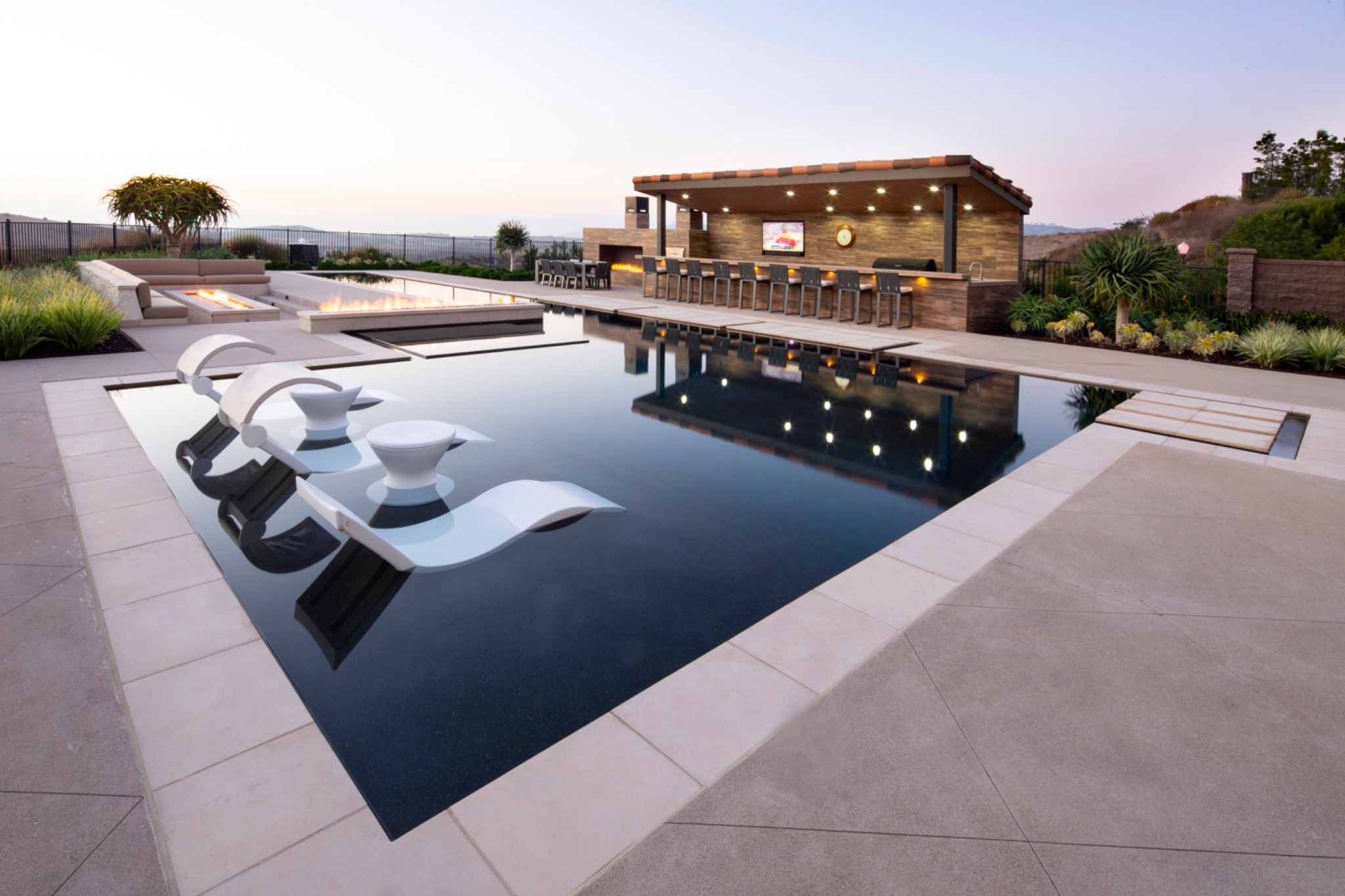 Luxury pool with tanning ledge, fire feature, and outdoor bar