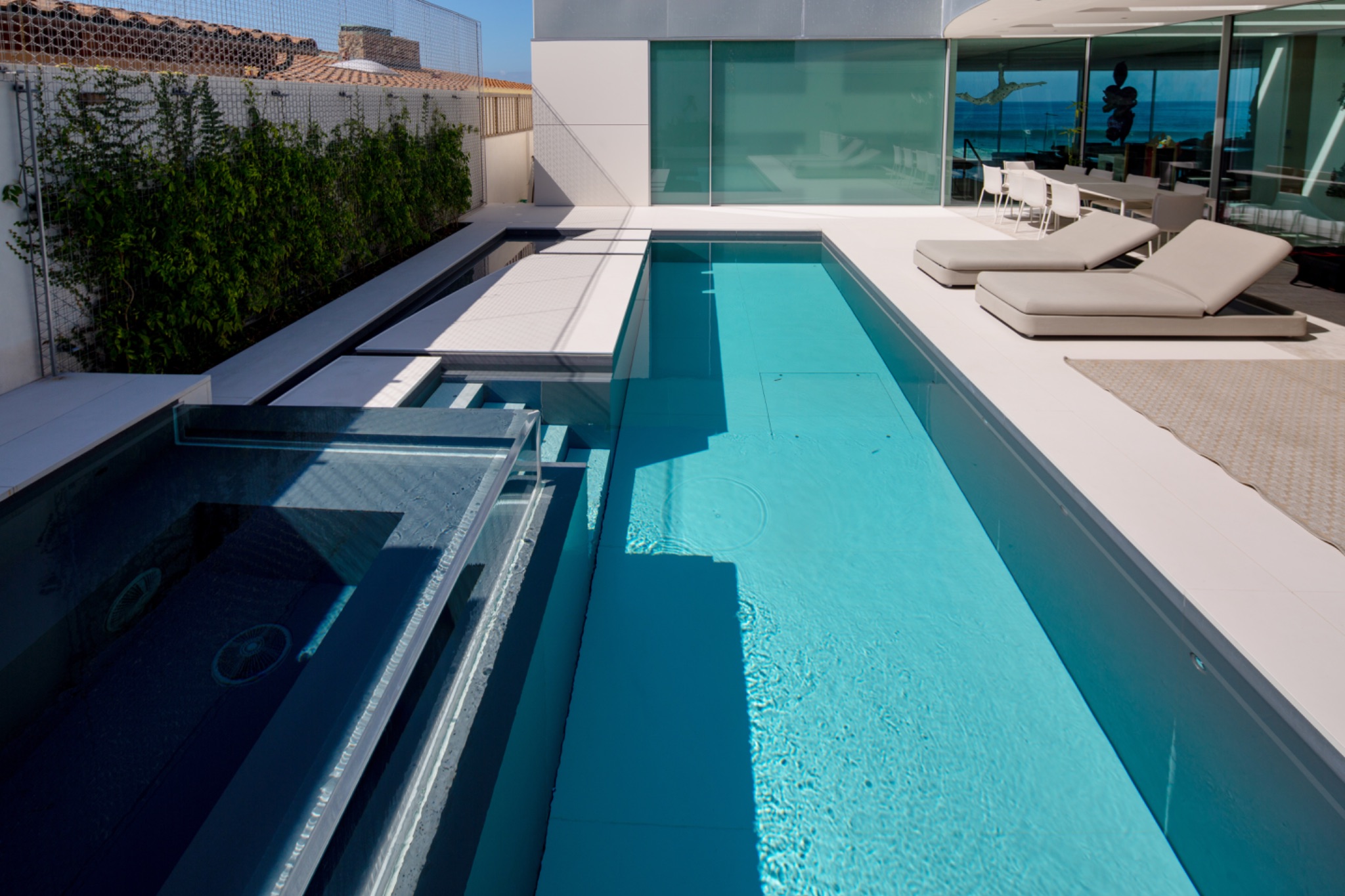 Modern minimalist lap pool with spillover spa and loungers