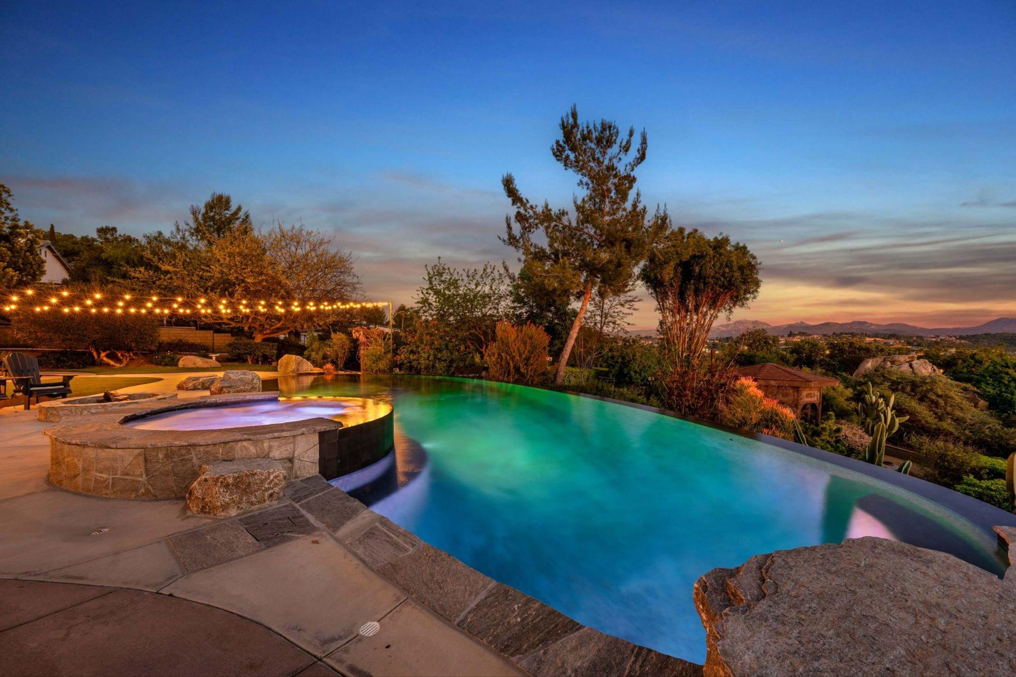 Freeform infinity edge with ambient evening lighting over garden views