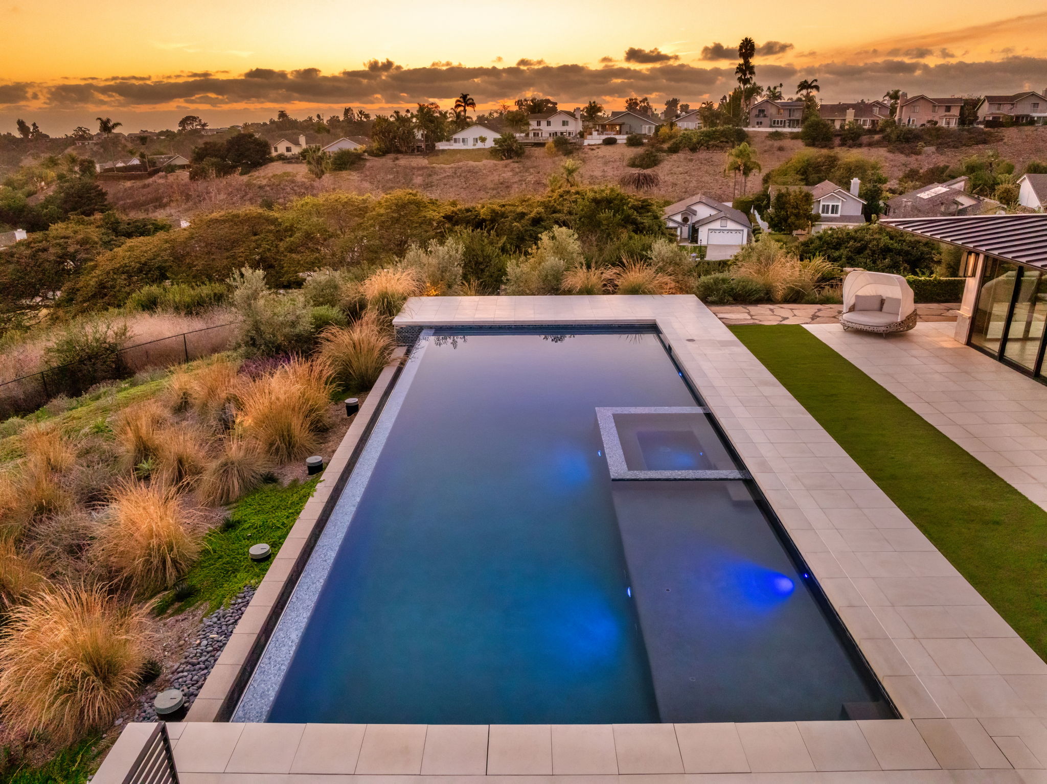 Infinity-edge concrete pool with built-in spa at sunset