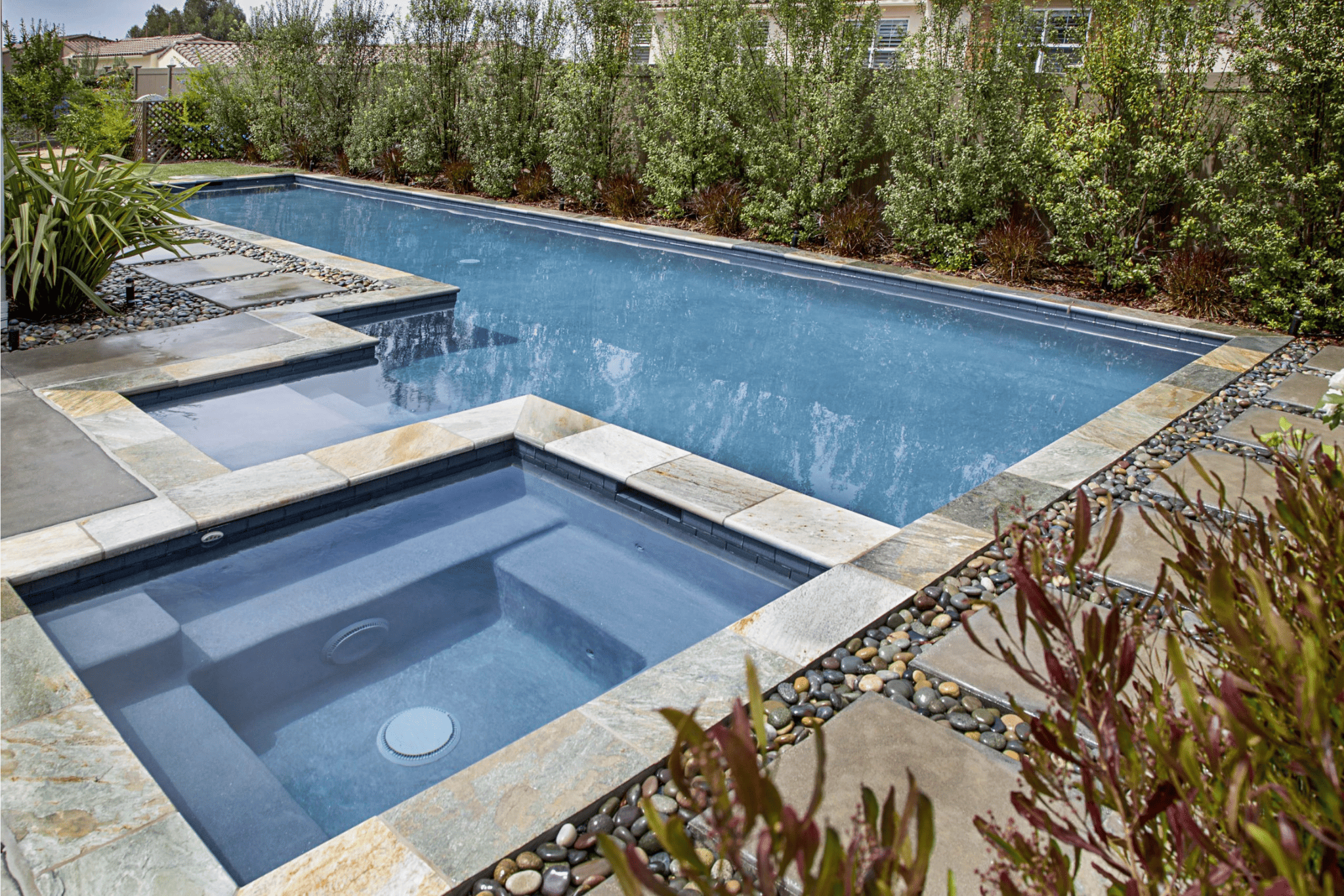 A luxury pool with shrubbery surrounding it