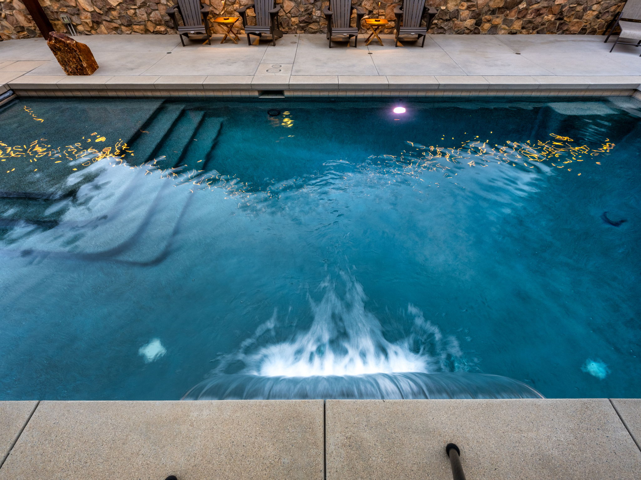 Concrete pool with fountain feature and stone deck seating