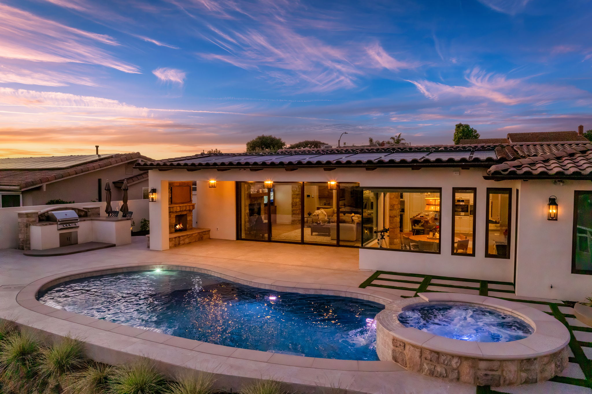 Luxury freeform pool and spa with outdoor kitchen at sunset