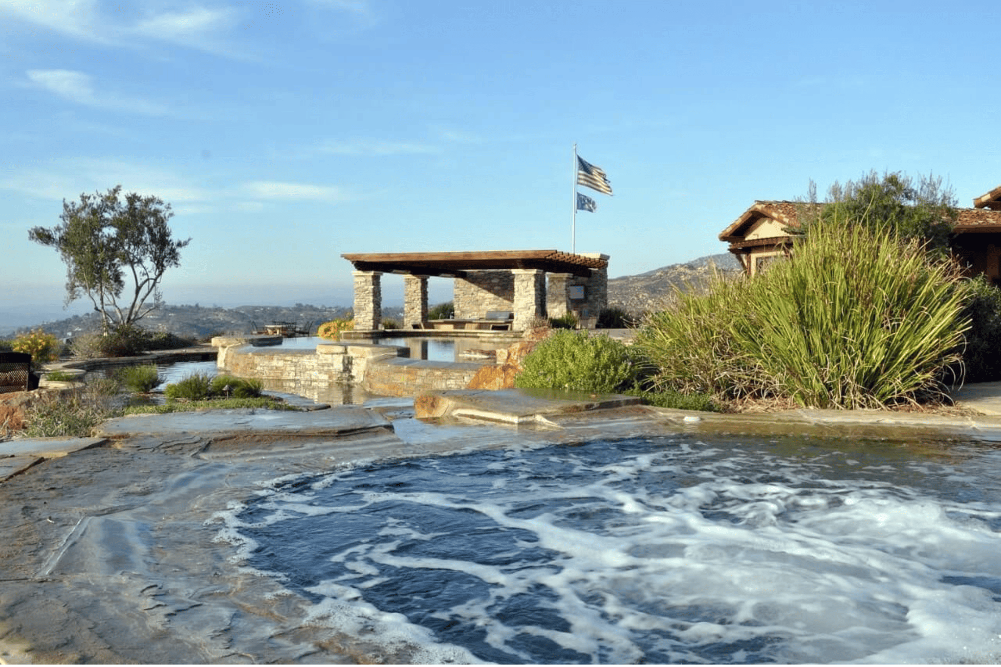 A luxury pool with an American flag attached to an outhouse 
