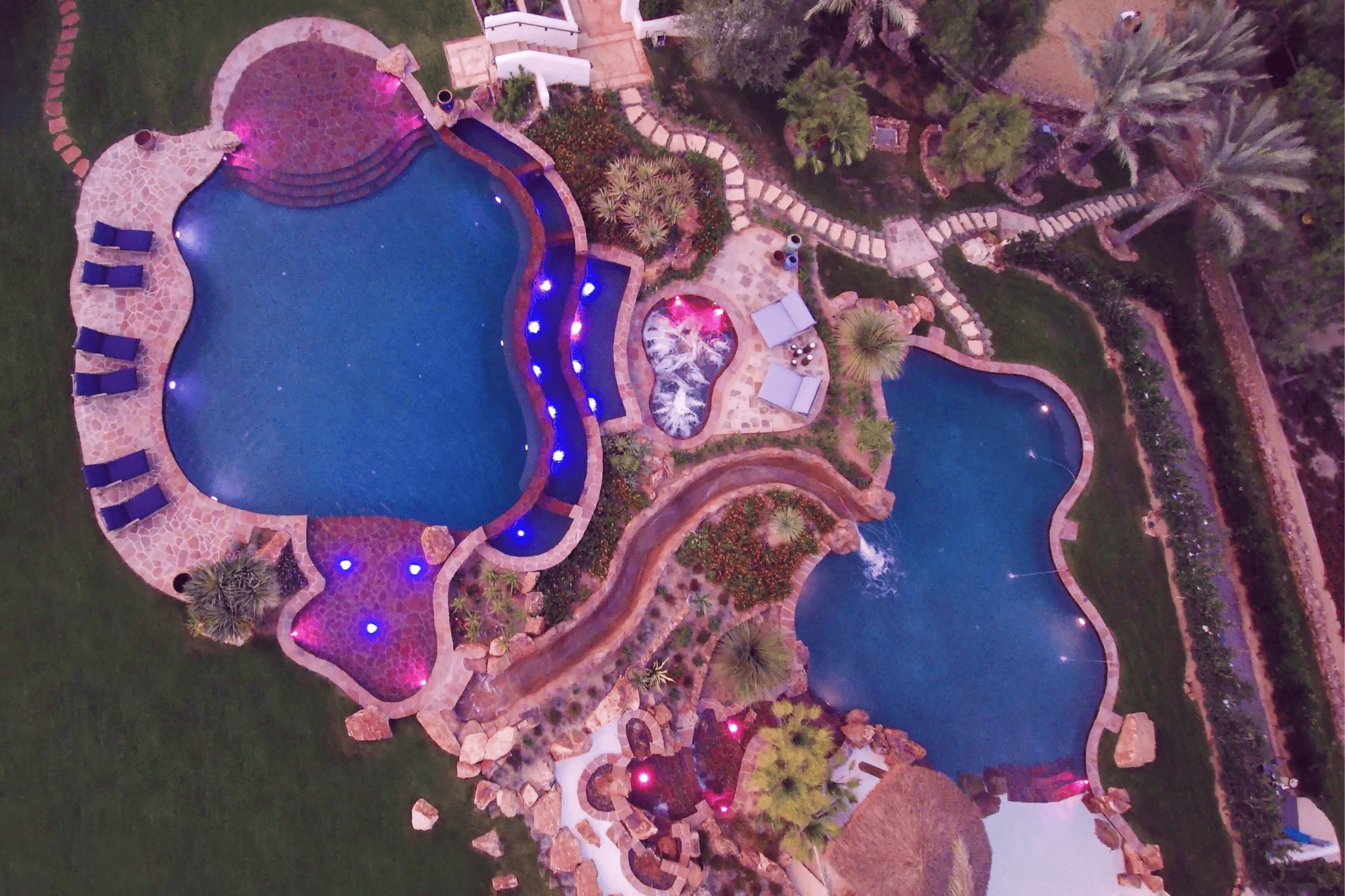 An aerial view of luxury pools with purple ambient lighting