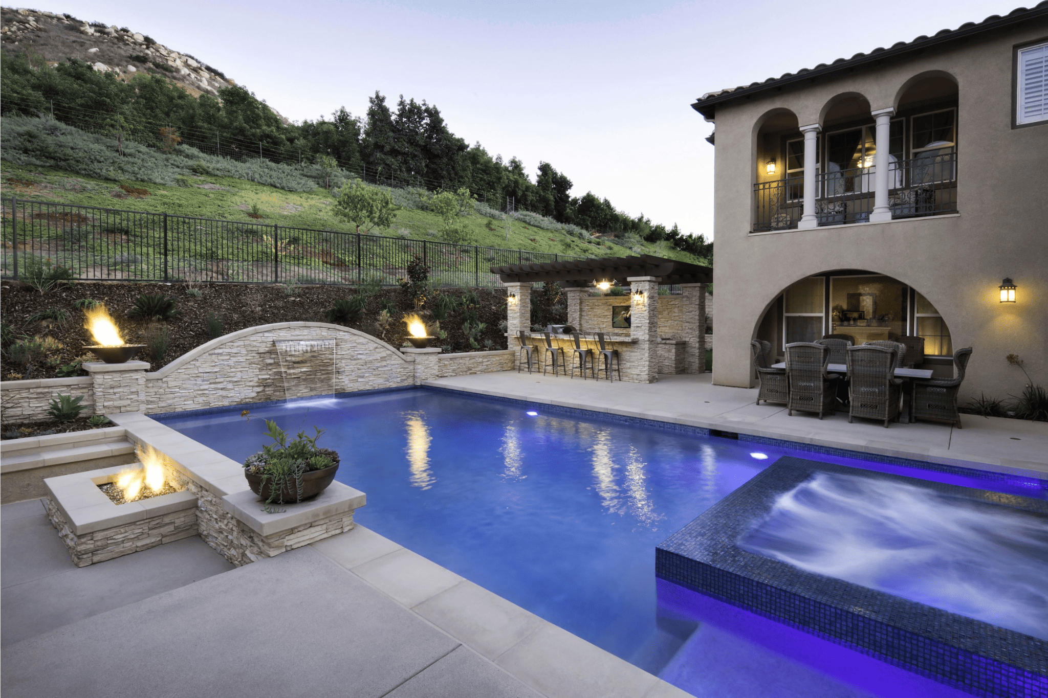 A luxury pool with pot fires surrounding it