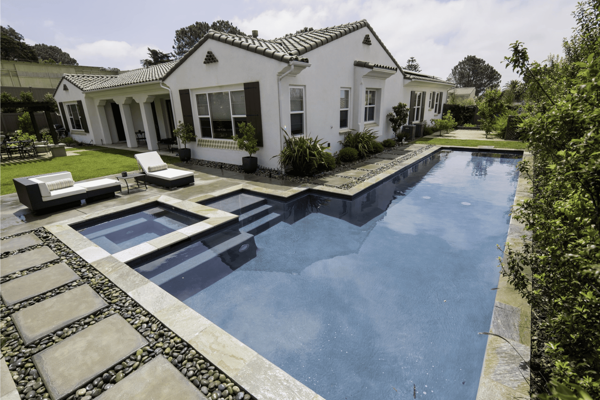 A luxury pool with rockeries and deck chairs nearby 