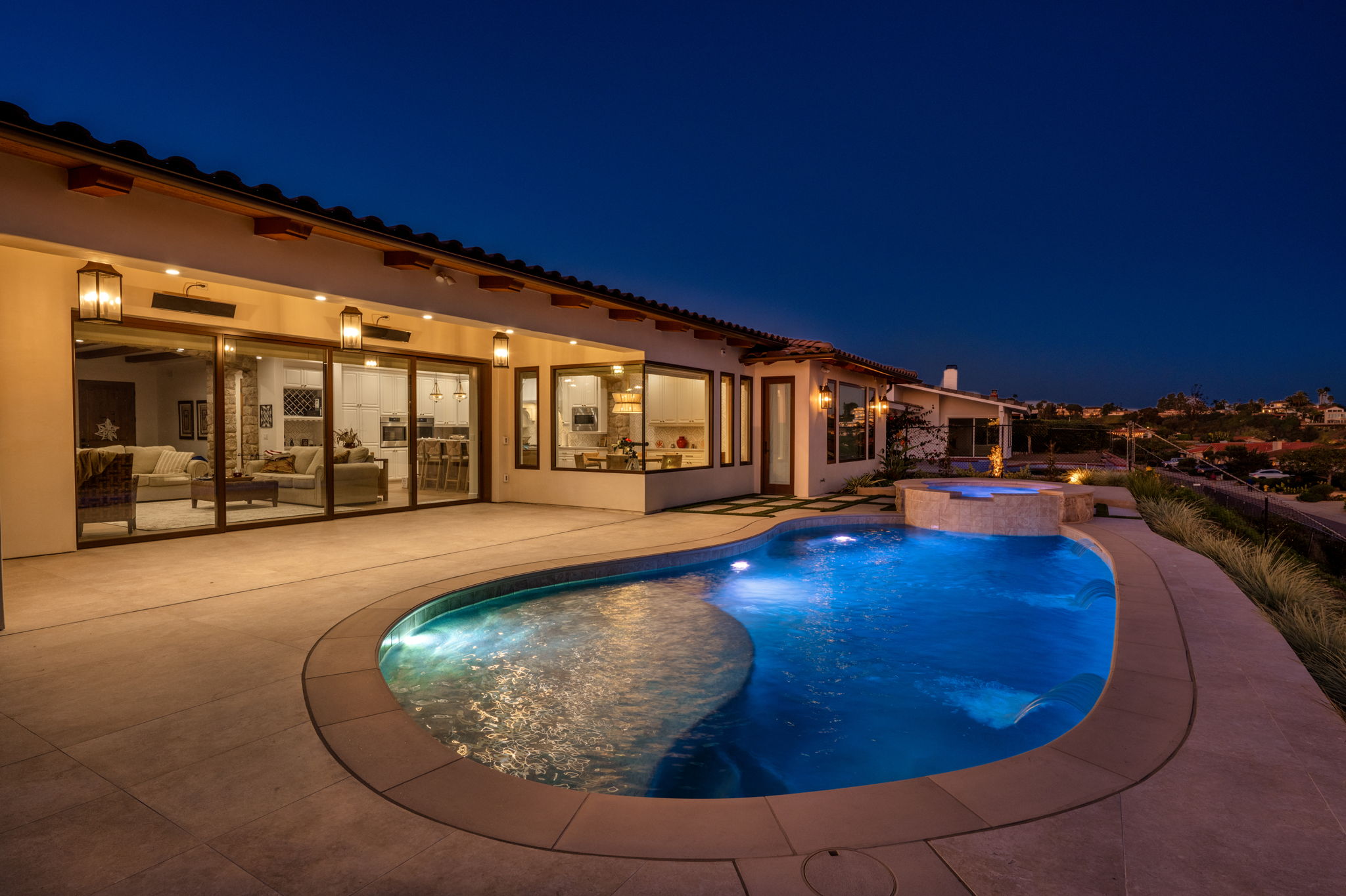 Illuminated freeform concrete pool and spa at night.