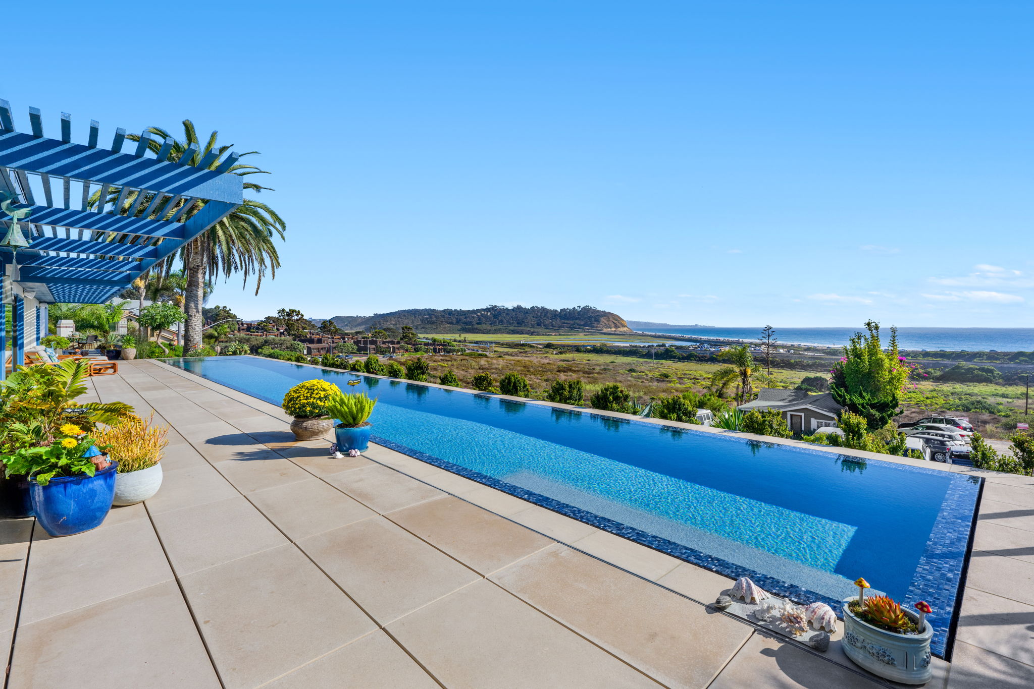 Infinity-edge lap pool with coastal ocean view and pergola