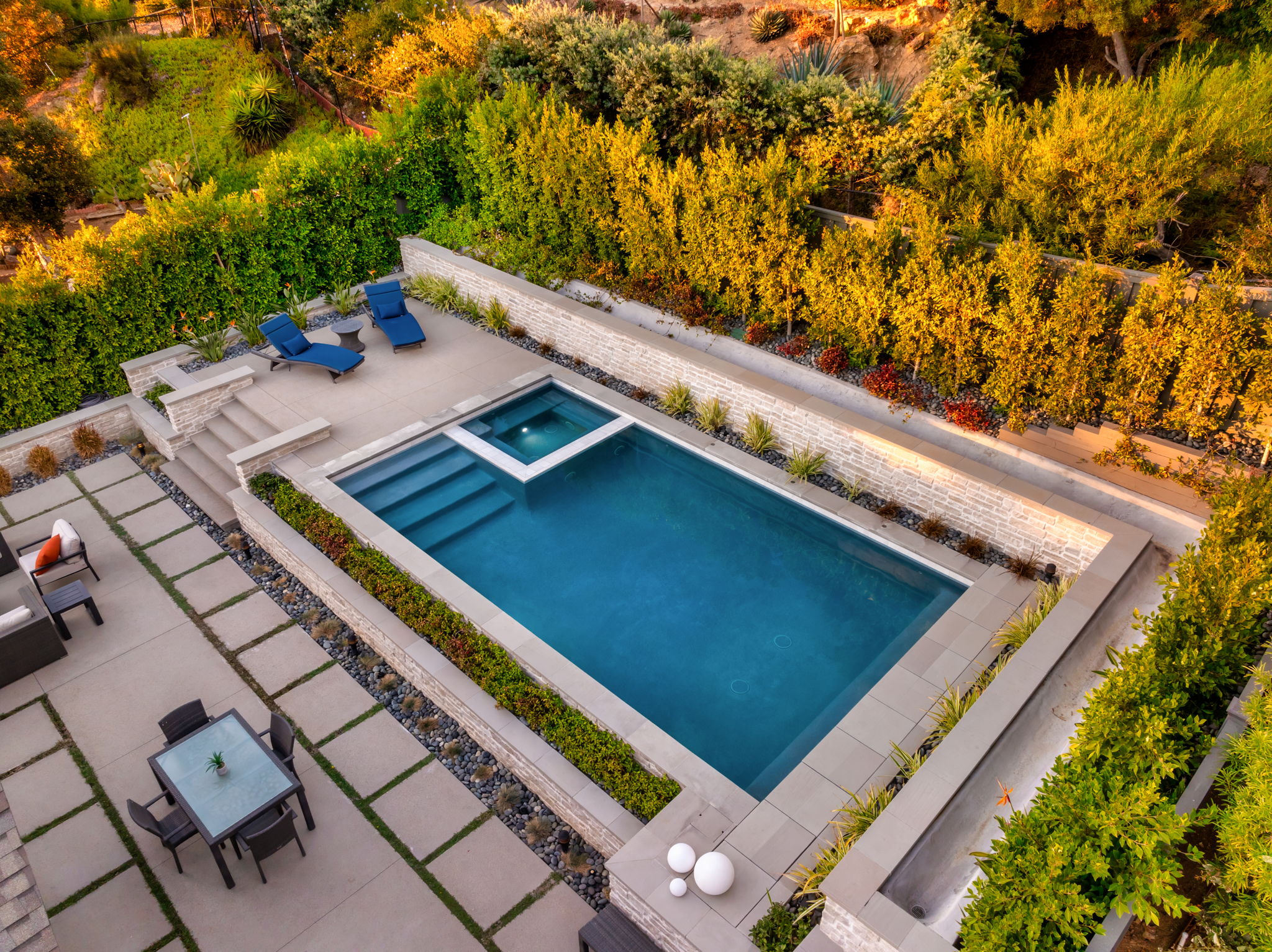 Geometric pool with spa and hillside landscaping from above