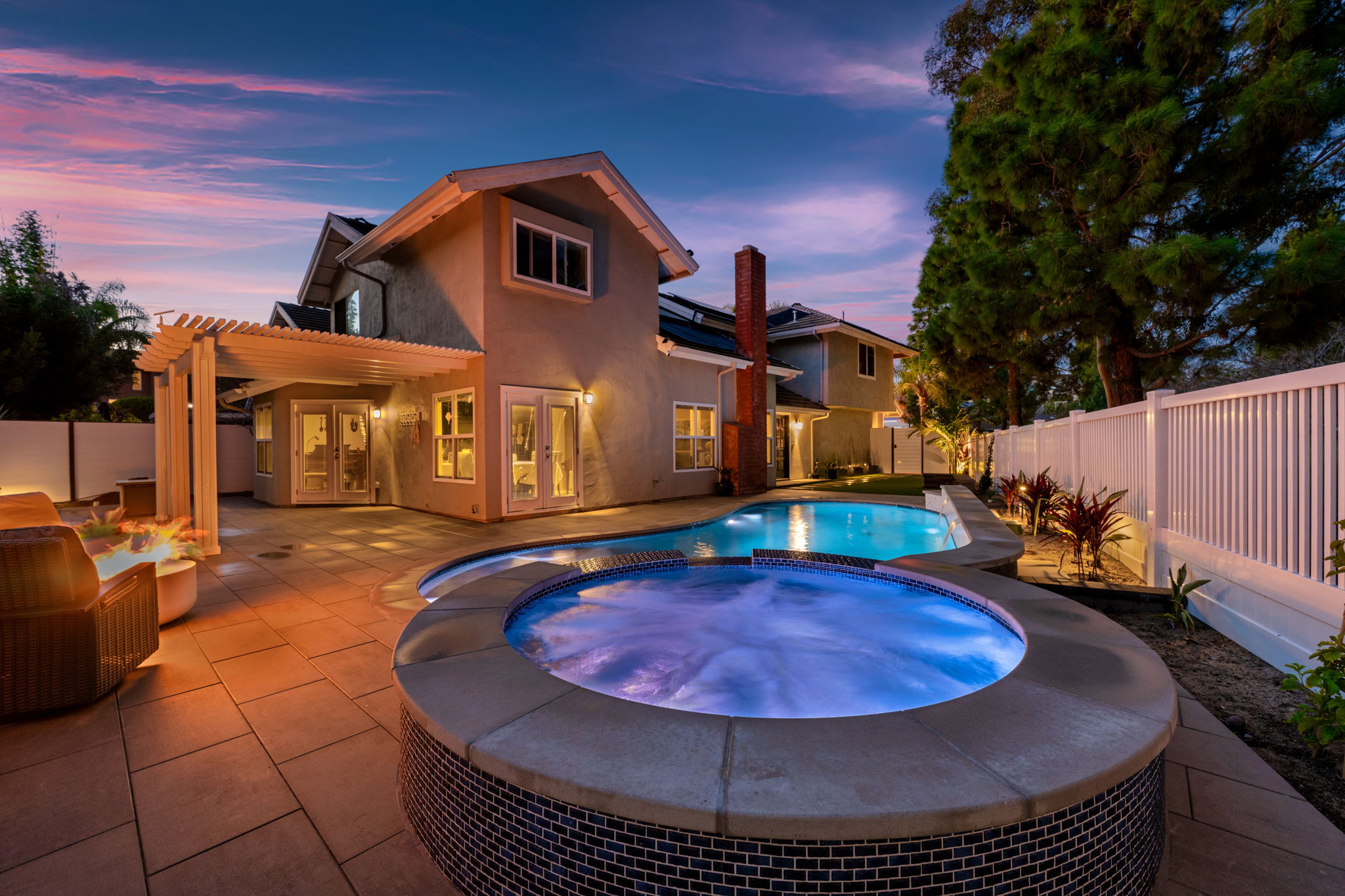 Freeform inground pool and spa lit up at evening
