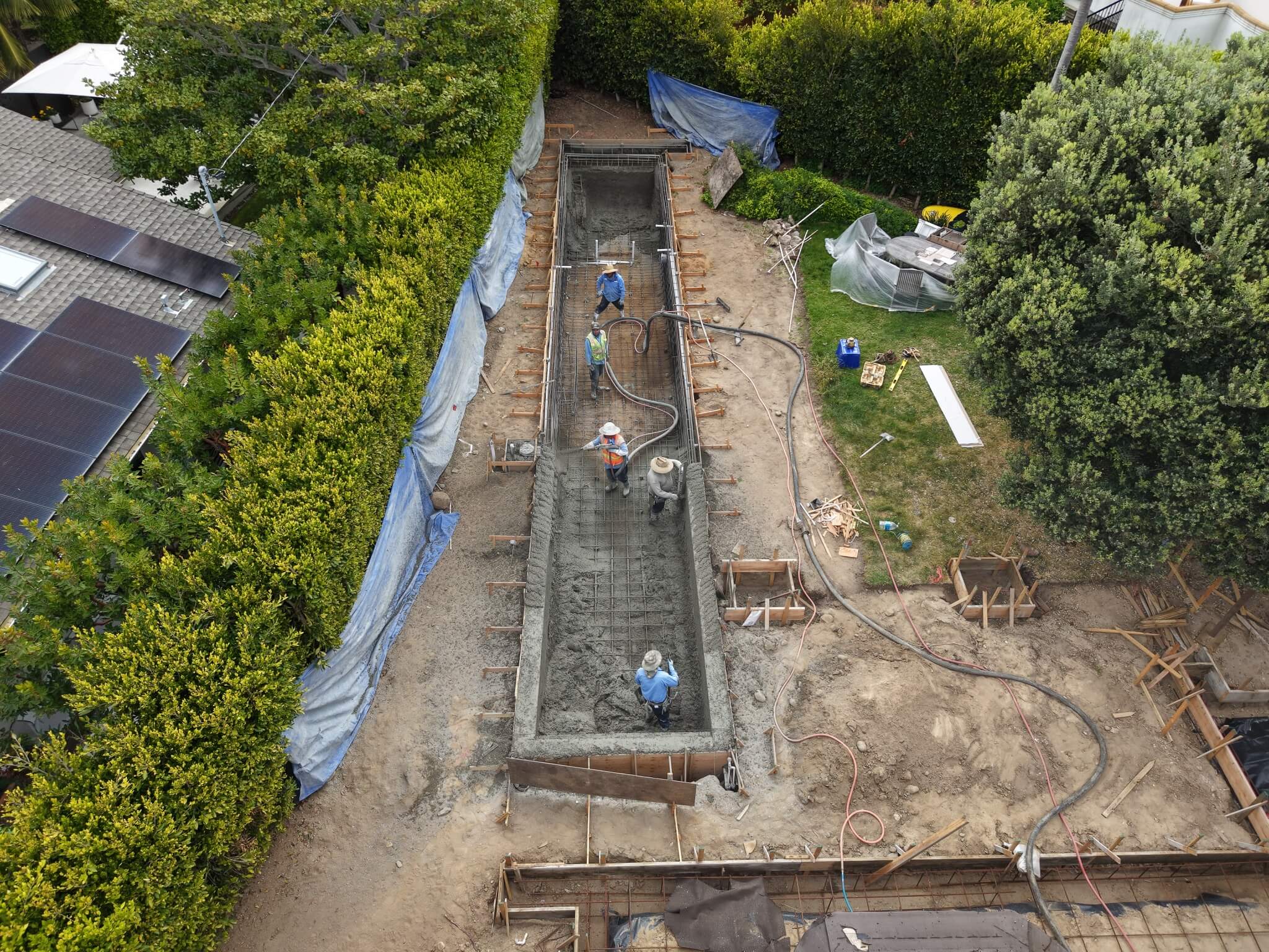 Pool remodeling crew applying shotcrete to the rebar-reinforced shell during the structural stage of a swimming pool renovation