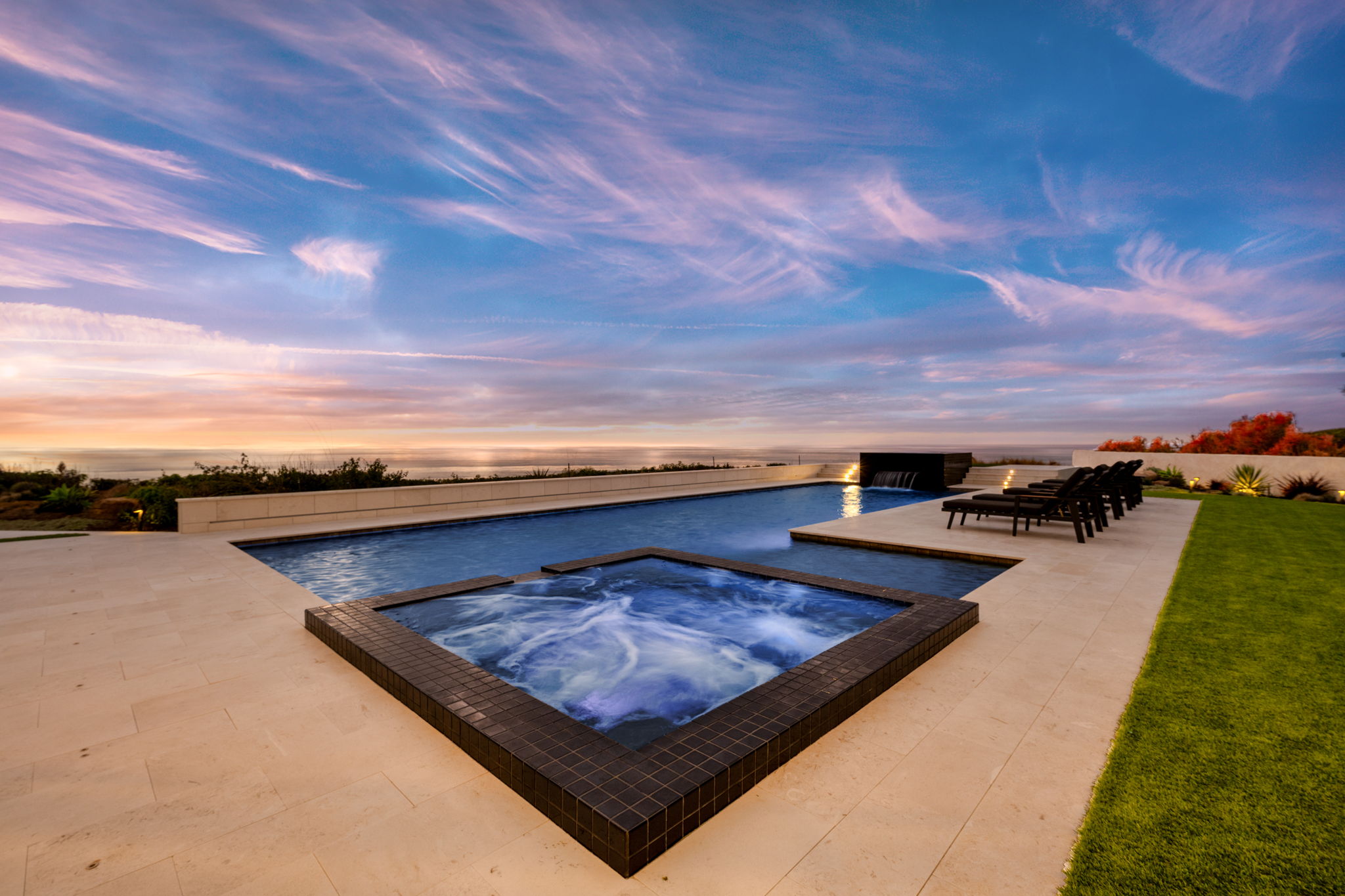 Attached spillover spa beside a rectangular pool with ocean views, one of the most popular pool makeover ideas in California