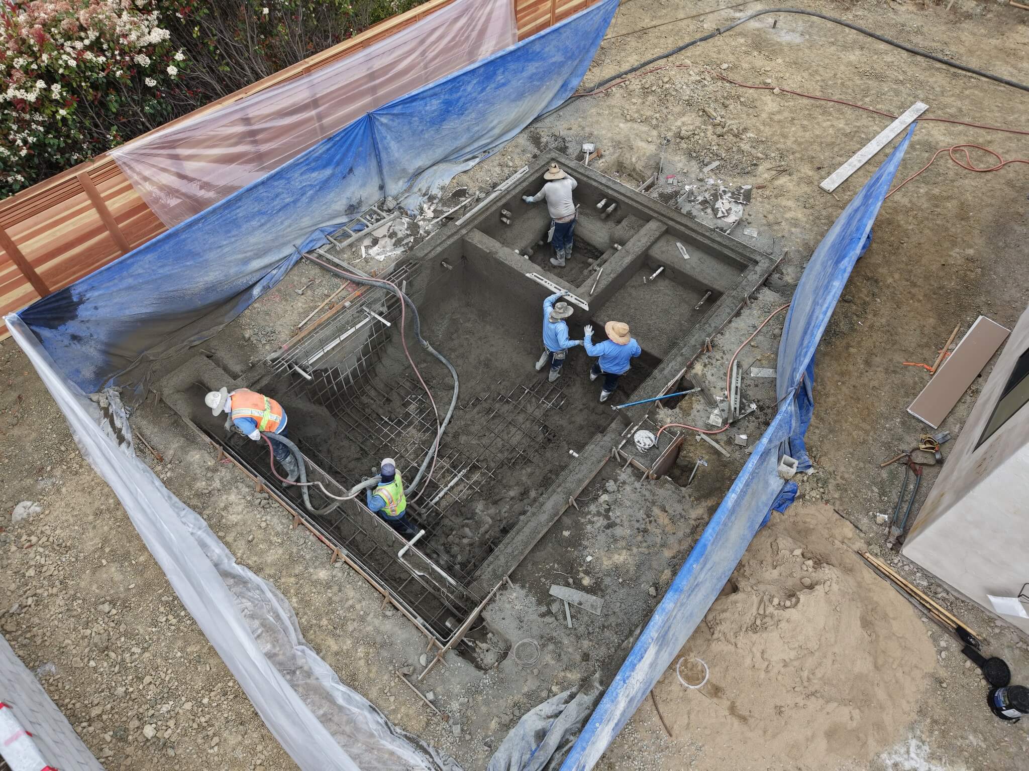 Swimming pool remodel crew shaping shotcrete inside a pool and attached spa, the structural stage of the pool remodeling process